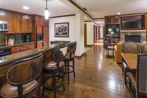 A spacious kitchen with wooden cabinets, a granite countertop, and a bar area with leather bar stools.