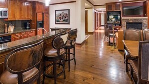 A spacious kitchen with wooden cabinets, a granite countertop, and a bar area with leather bar stools. - Aspen Ritz Carlton 3 bed 04 (Aspen)