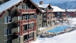 A multi-story hotel with balconies, a pool area, and a snowy mountain backdrop. - Aspen Ritz Carlton 3 bed 04 (Aspen)