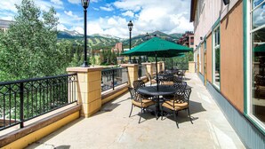 A balcony with outdoor seating, a view of mountains, and a building with large windows.