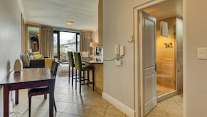 Habitación de hotel con comedor, baño con ducha y vista al exterior.