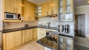 Una cocina moderna con armarios de madera, encimera de granito, electrodomésticos de acero inoxidable y microondas integrado.