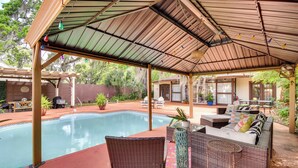 A covered outdoor area with a pool, wicker furniture, and a patio table. - Walk to Beach! Romantic 'Deja View' Apt in Biloxi (Biloxi)