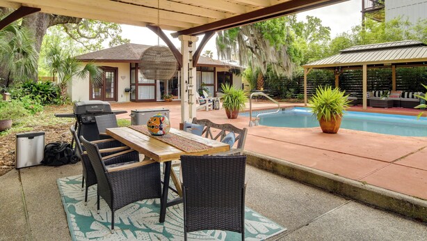 An outdoor patio with a wooden table and chairs, a grill, and a pool. - Walk to Beach! Romantic 'Deja View' Apt in Biloxi (Biloxi)