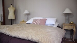 A bedroom with a large bed, two bedside tables with lamps, a dresser, and a mannequin. - Enjoy a relaxing stay (Fossès-et-Baleyssac)
