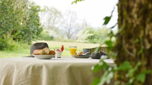 A table set outdoors with breakfast items including bread, yogurt, and juice. - Enjoy a relaxing stay (Fossès-et-Baleyssac)