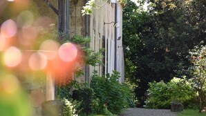 A garden with a stone wall, a wooden fence, and various shrubs. - Enjoy a relaxing stay (Fossès-et-Baleyssac)