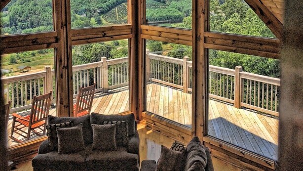 A wooden cabin with a large balcony, offering a view of a forested mountain landscape. - AWESOME View 2500 sqft decks 8 person Spa mins to Blue Ridge Pkway & New River (Fleetwood)