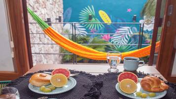 A breakfast table with a view of a blue wall and a hammock.