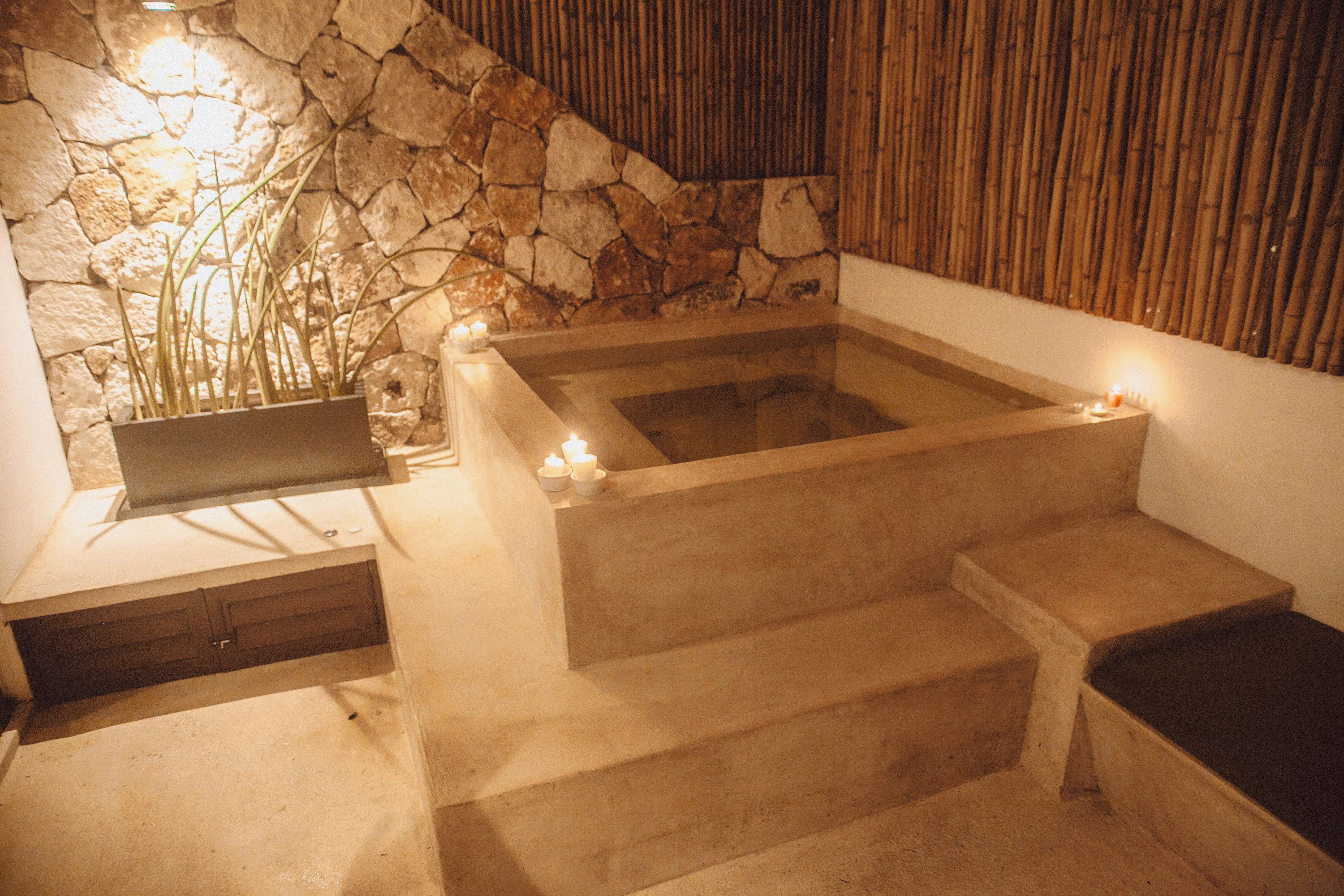 A stone wall, a bathtub, and a wooden bench.