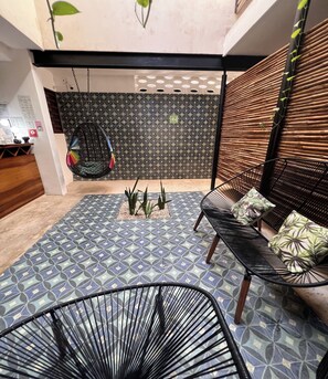 A modern interior with a patterned floor, black metal chairs, a hanging chair, and a bamboo wall. - Collection O Latino Boutique Tulum (Tulum)