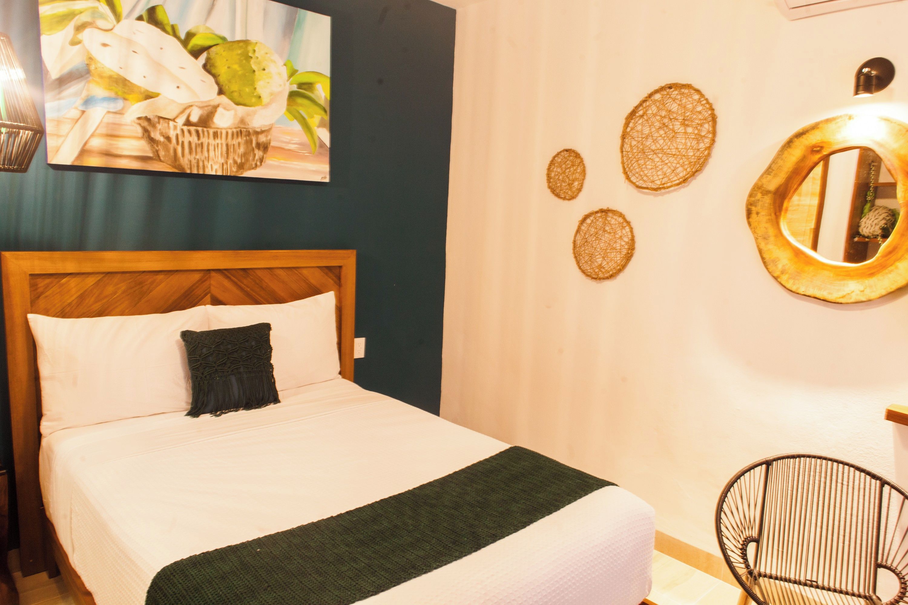 A hotel room with a bed, a chair, a wall with decorative items, and a painting.