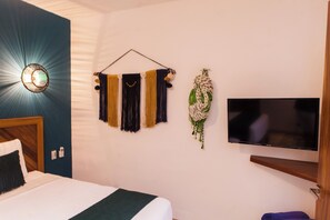 Quarto de hotel com cama, televisão fixada na parede e decorações nas paredes.