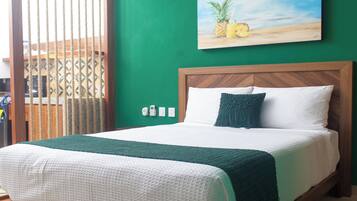 A bed with a wooden frame, a green wall, and a painting of pineapples.