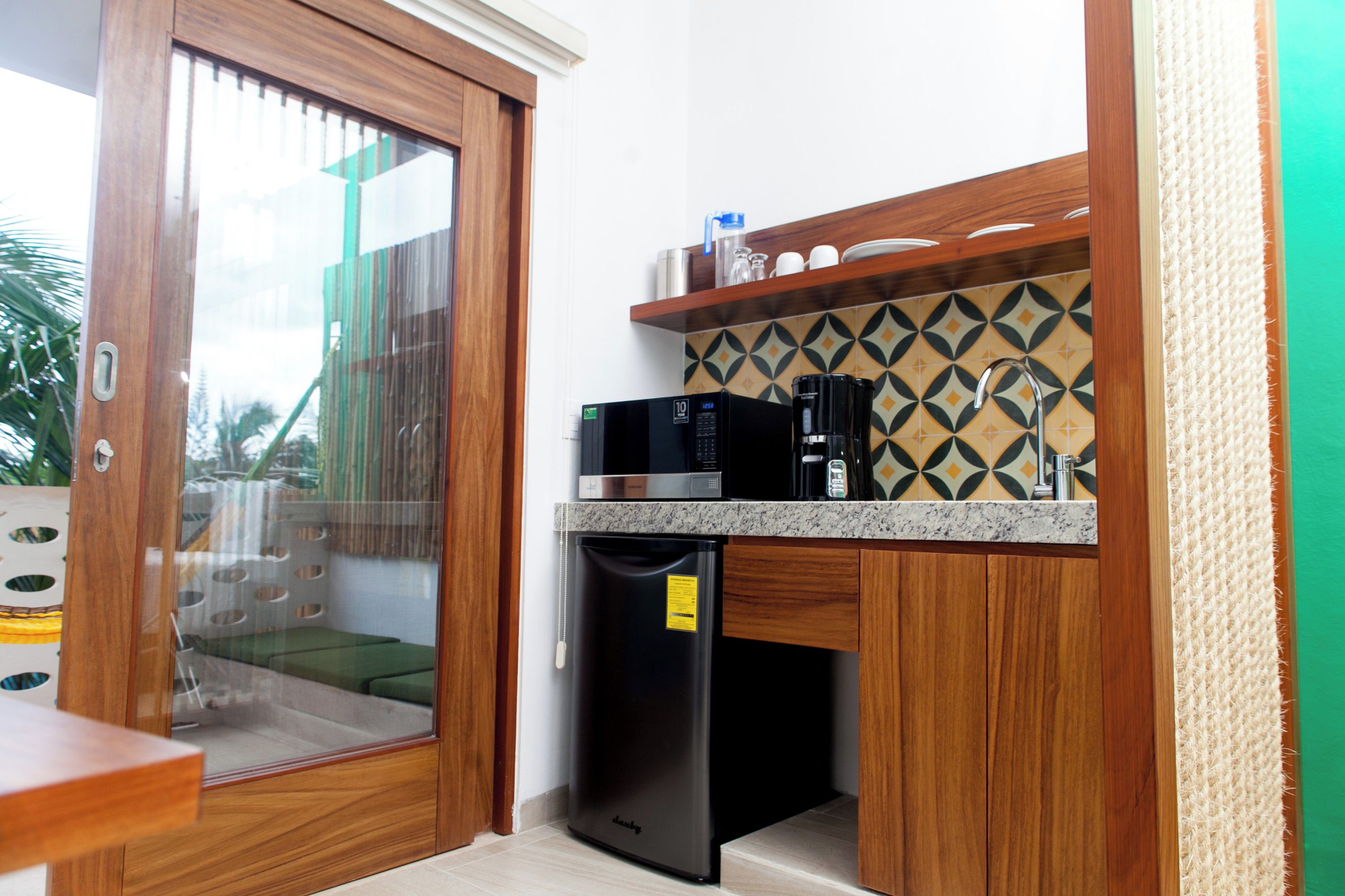 A compact kitchen with a microwave, coffee maker, and a refrigerator.