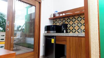 A compact kitchen with a microwave, coffee maker, and a refrigerator.