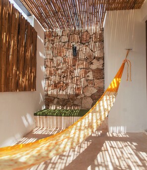 A hammock in a sunlit room with a stone wall and bamboo slats. - Collection O Latino Boutique Tulum (Tulum)
