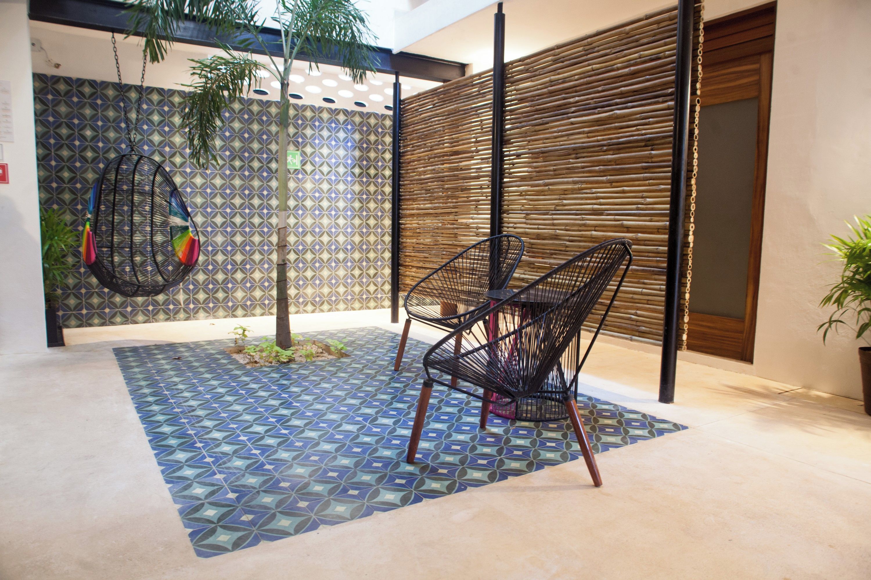 Una habitación con piso estampado, una silla colgante y una pared de bambú.