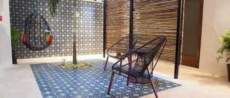 Quarto com piso estampado, cadeira suspensa e parede de bambu.