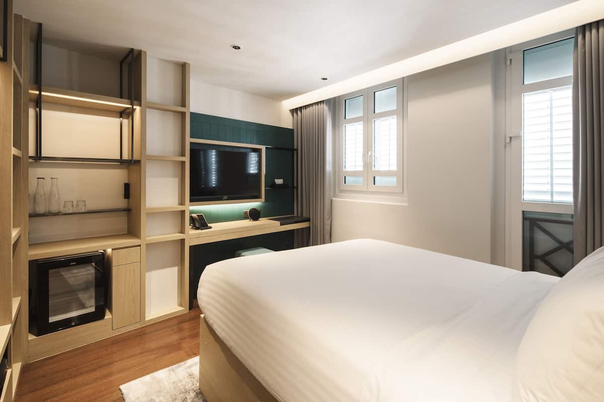A modern hotel room with a large bed, built-in TV, and a desk area.
