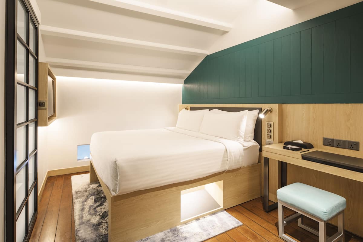 A bedroom with a bed, a desk, and a bench.