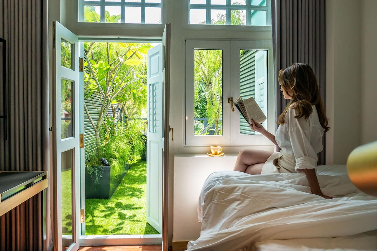 A room with a bed, a window, and a view of a garden.