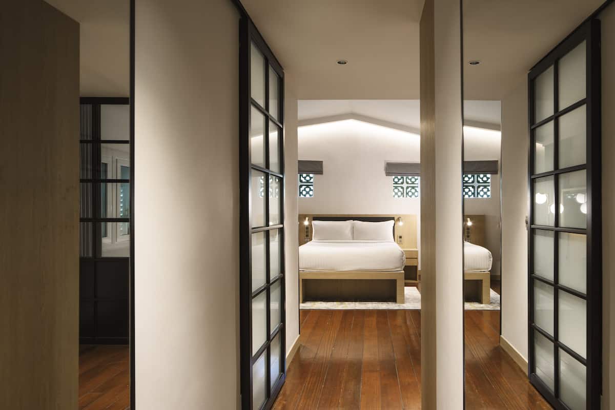 A modern bedroom with a large bed, bedside tables, and a wooden floor.