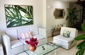 A living room with a white sofa, a glass coffee table, and a large abstract painting. - Colonial townhouse in the Old City with panoramic ocean views (Cartagena)