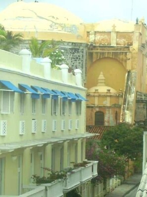 Une rangée de bâtiments traditionnels aux toits plats et aux murs blancs, avec une structure centrale surmontée d’un dôme et un bâtiment plus petit doté d’un toit en pente.