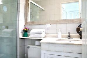 Une salle de bain avec un lavabo blanc, un miroir, un porte-serviettes et des toilettes.