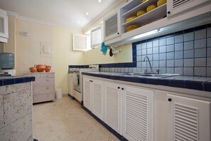 Kitchen features an oven, stainless steel sink, and dark blue tile countertops.