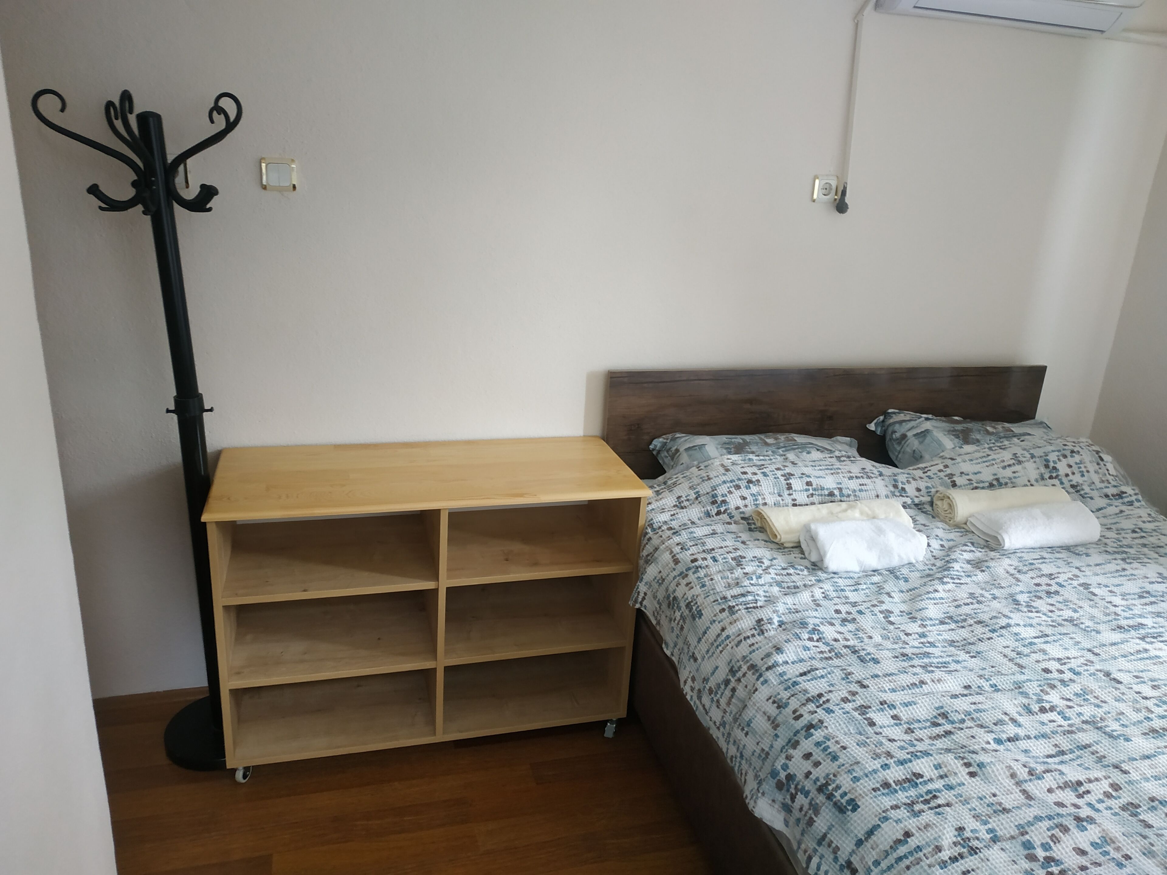Une chambre avec une table de chevet en bois, un lit avec une literie à motifs et une lampe de sol noire.