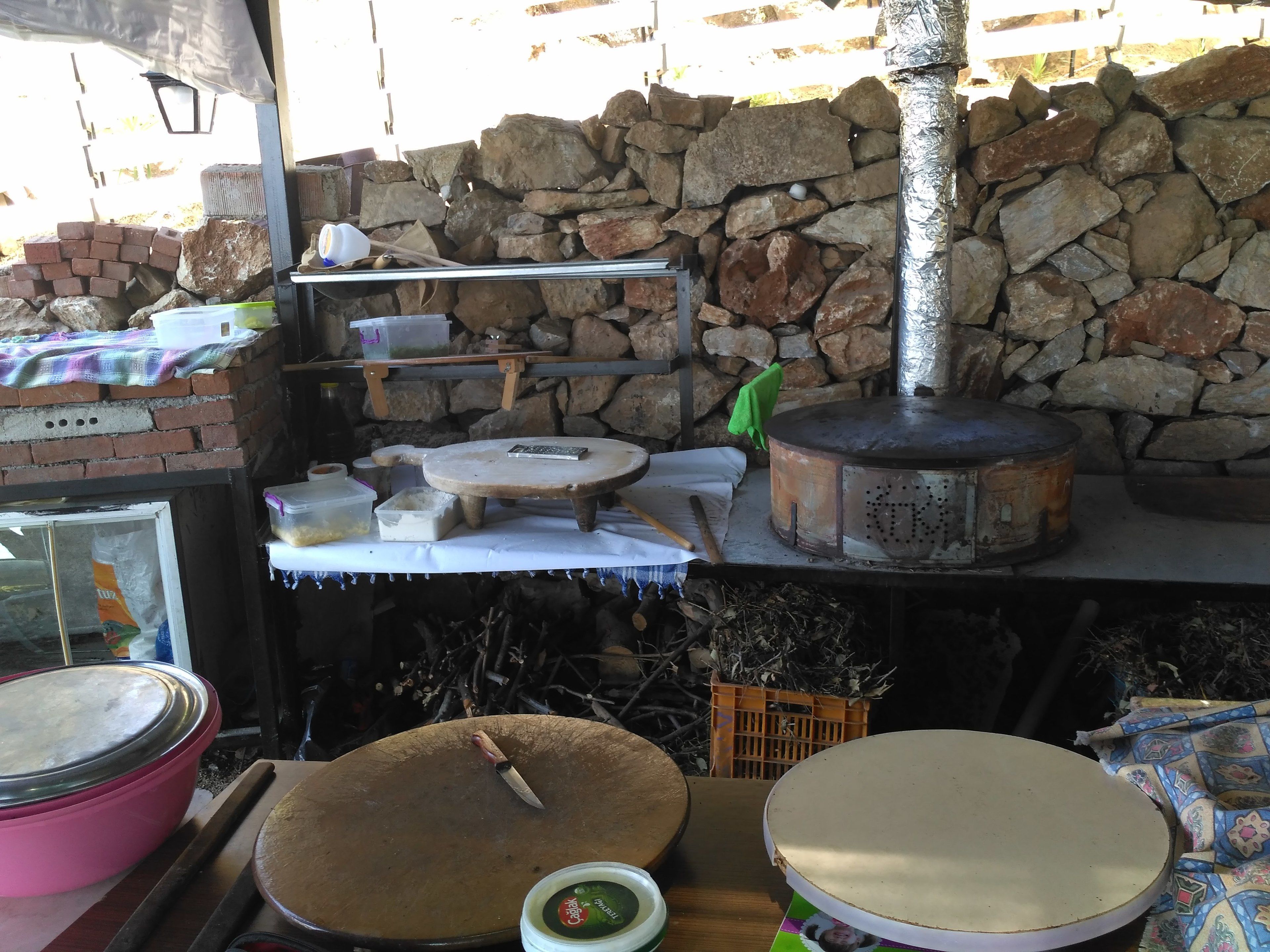 Une cuisine rustique aux murs de pierre, dotée d’un four en briques et de divers ustensiles de cuisine.
