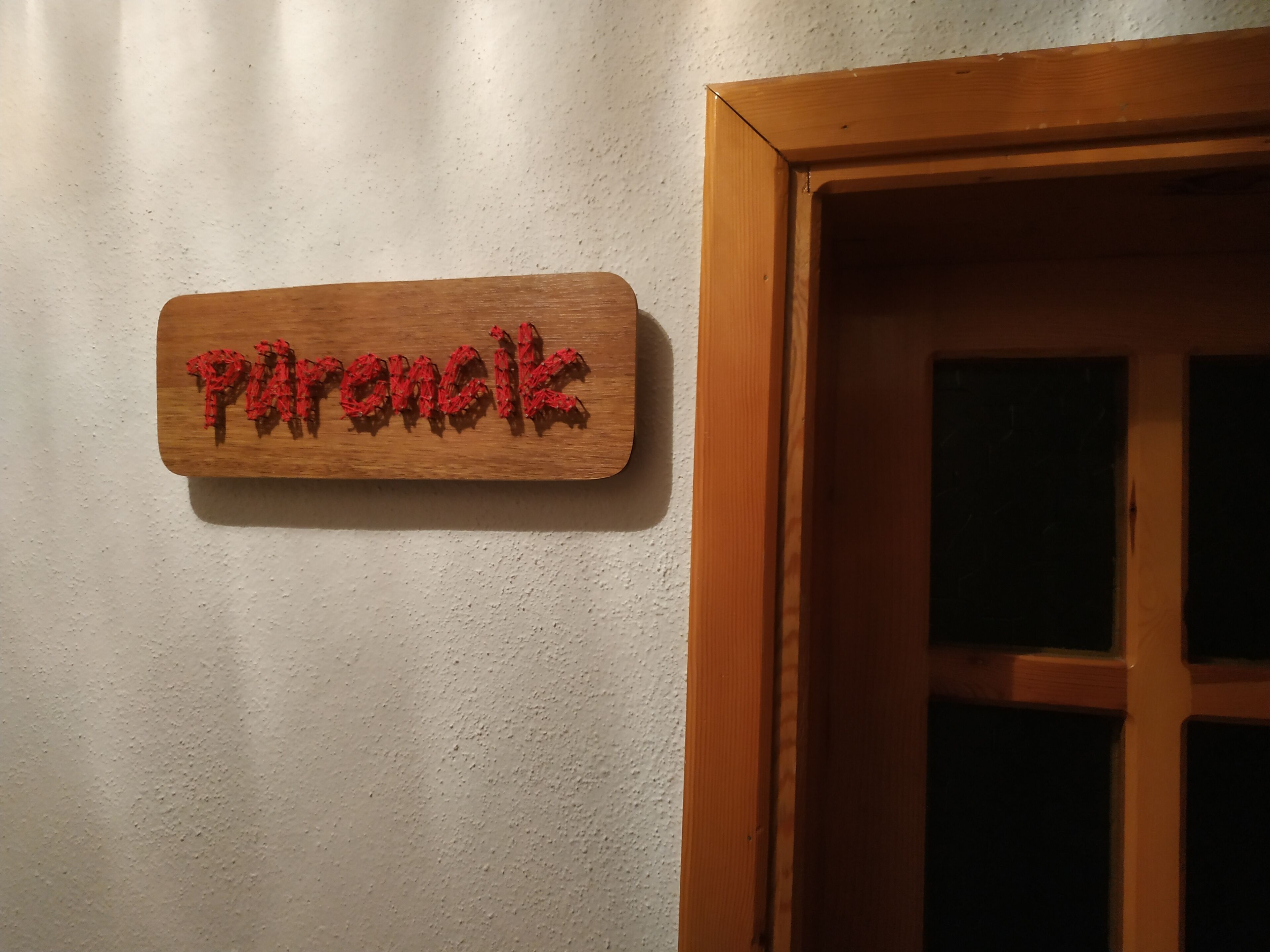 A wooden sign with the word "Piranoki" on a textured wall.
