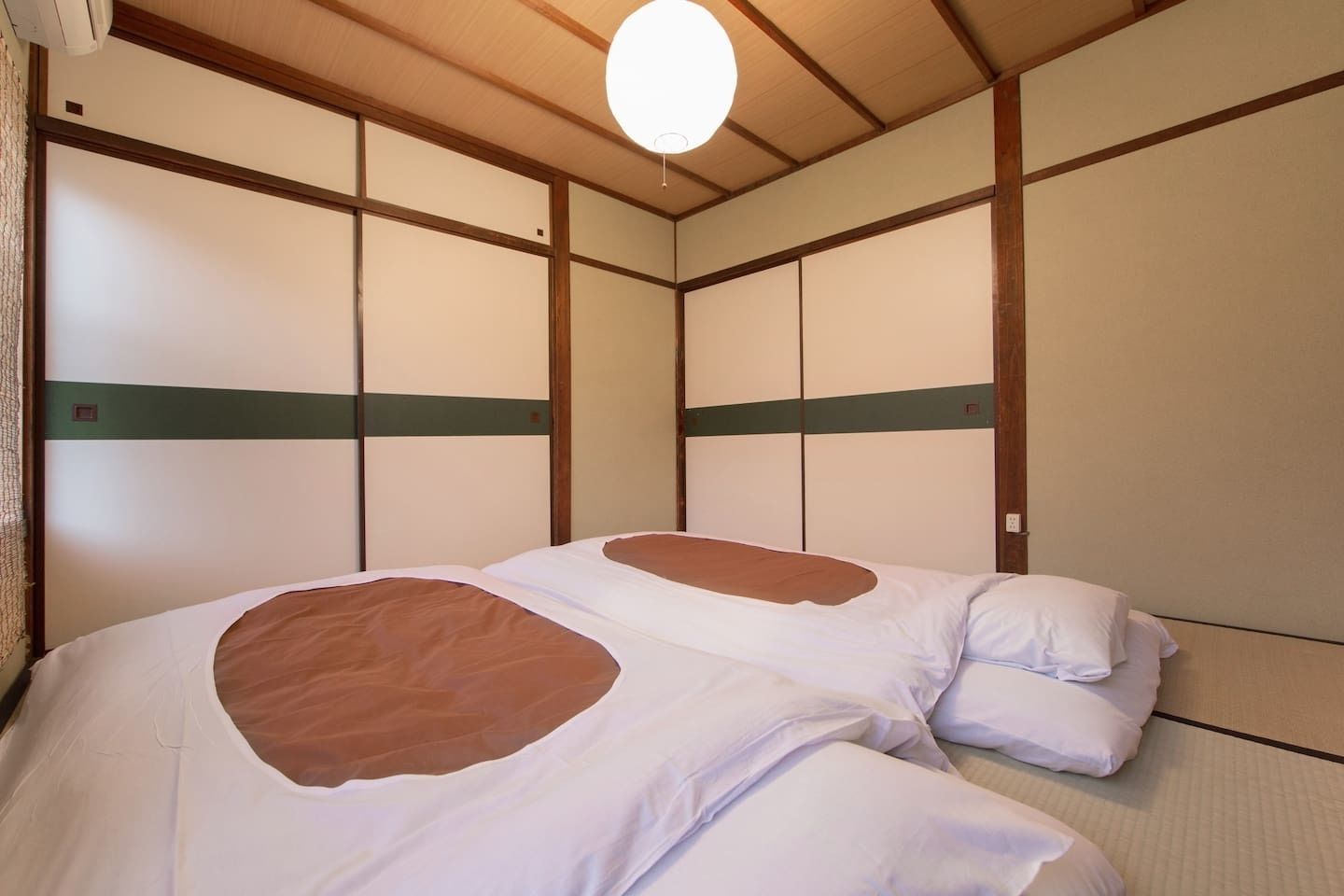 Une pièce de style japonais traditionnel, avec un sol recouvert de tatamis, un plafond bas en bois et des paravents en papier de riz (shoji).