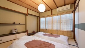 A traditional Japanese room with tatami flooring, a futon bed, a shoji screen, and a hanging light fixture. - Kyo Machiya Nijo (Kyoto)