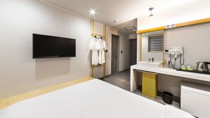 A hotel room with a bed, a TV mounted on the wall, a sink with a mirror, and a small kitchenette. - Hannam 67 (Seoul)
