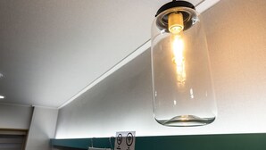 A hanging light fixture with a glass enclosure and a visible filament bulb. - Hannam 67 (Seoul)