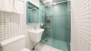 A bathroom with a white sink, a glass-enclosed shower, and a mirror above the sink. - Hannam 67 (Seoul)