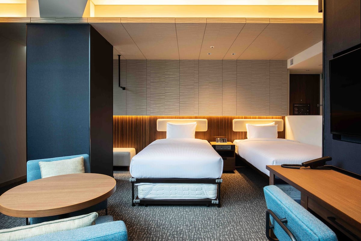 Une chambre d’hôtel avec deux lits, une table ronde et un téléviseur.