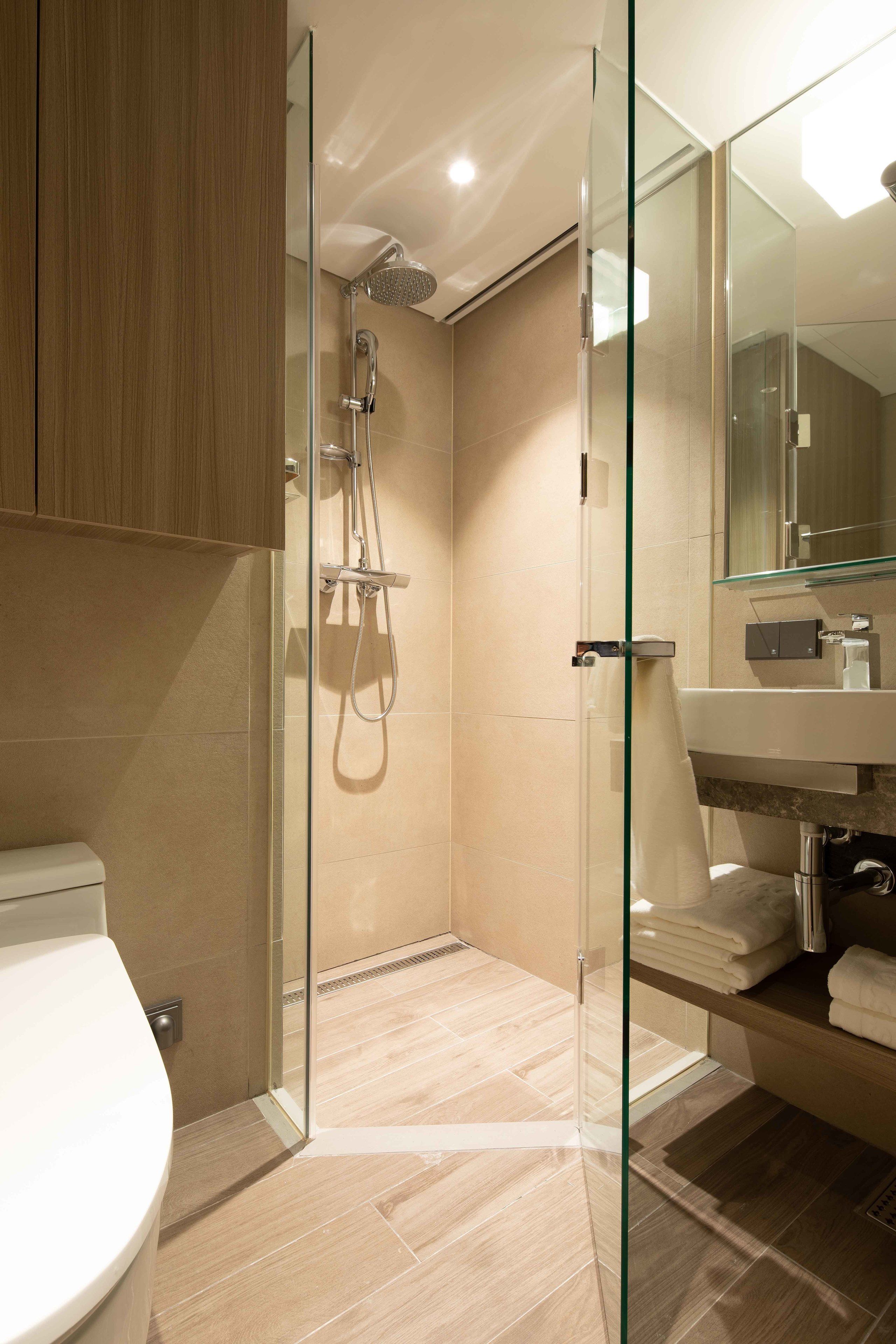 Une salle de bain moderne avec une douche à parois de verre, des toilettes et un lavabo avec un miroir.