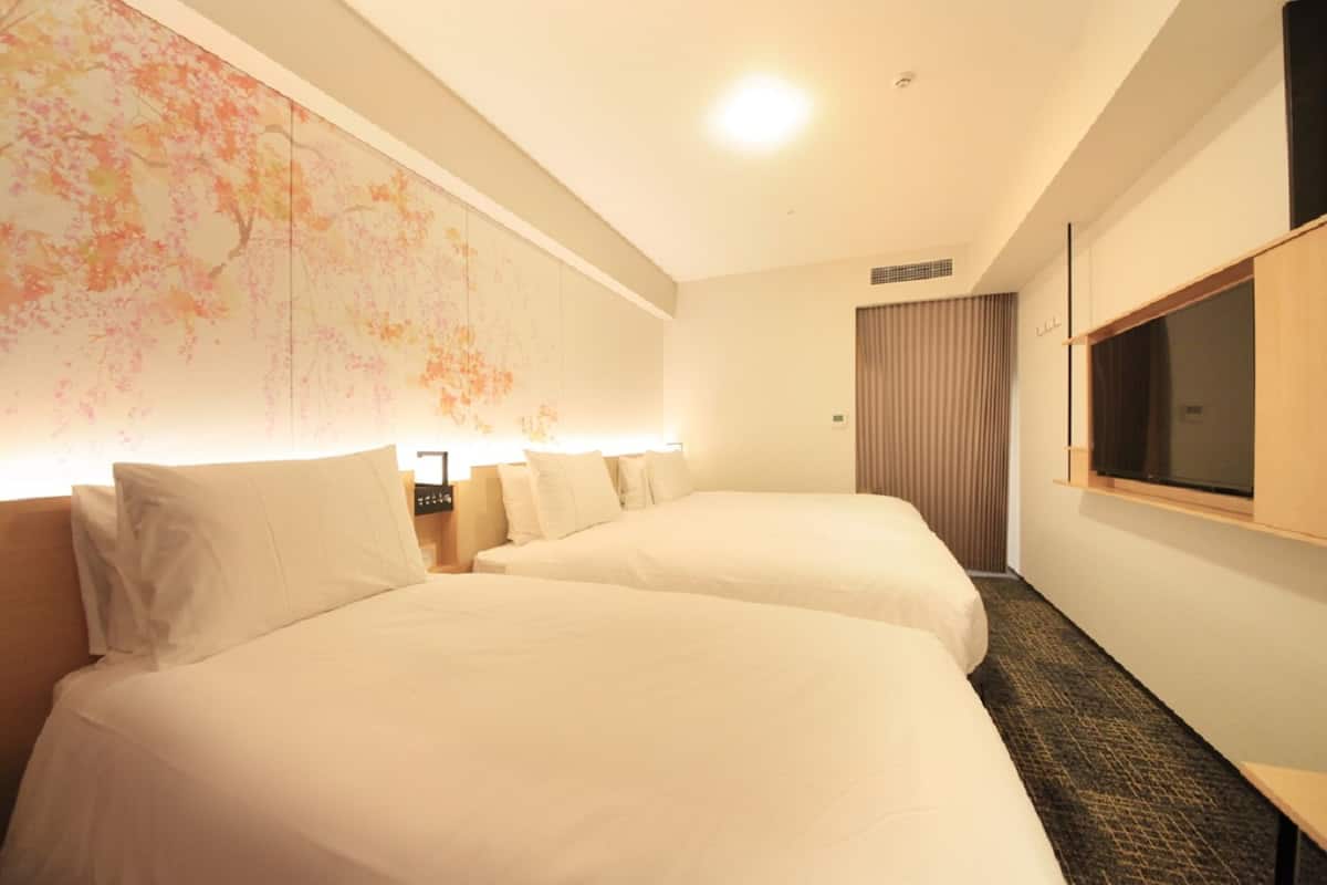 A hotel room with two beds, a large wall mural, a flat-screen TV, and a wooden cabinet.