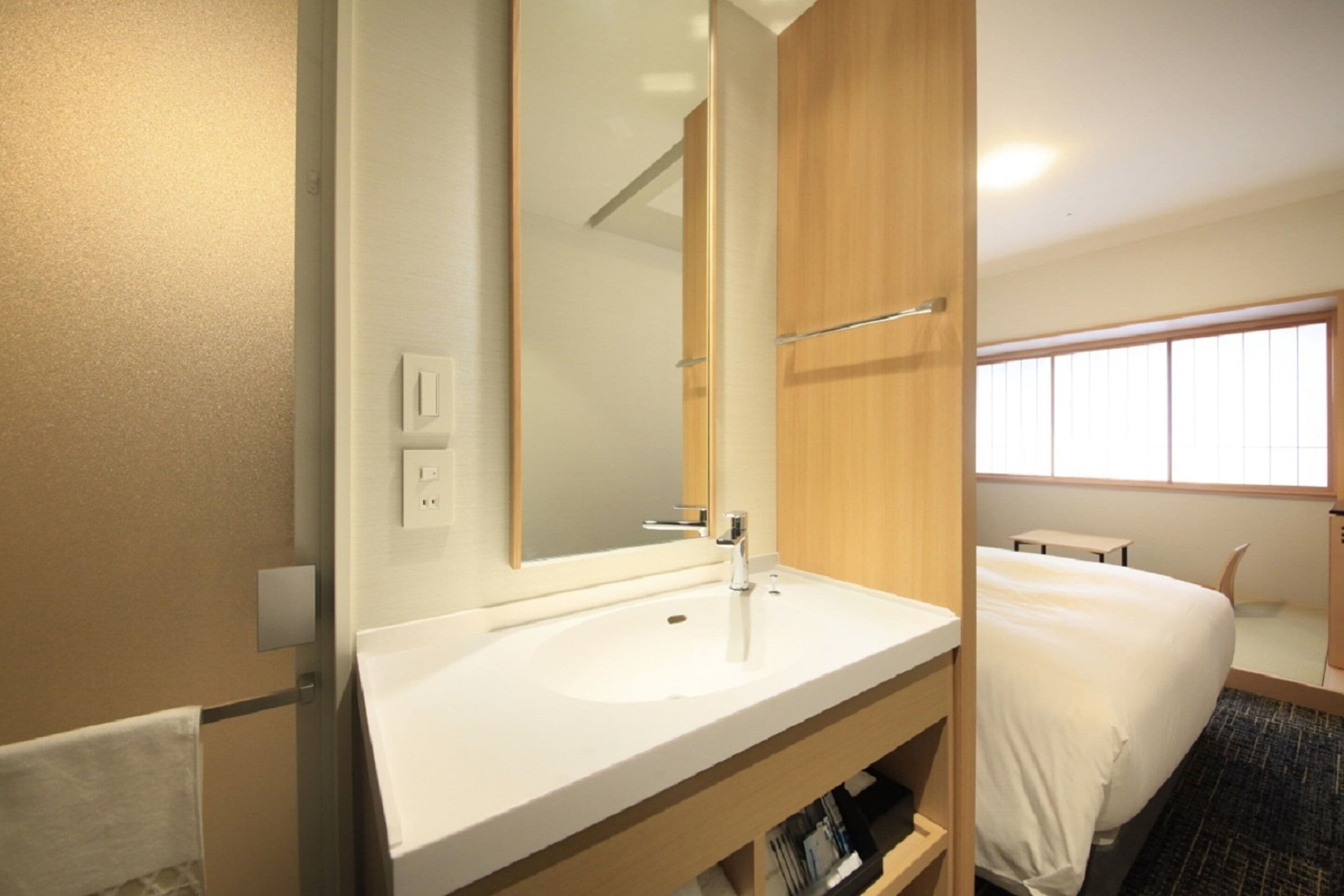 A hotel bathroom with a white sink, a large mirror, and a wooden vanity.