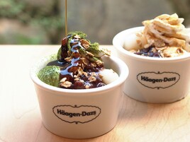 Two bowls of Häagen-Dazs ice cream with toppings, placed on a wooden surface.