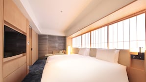 A hotel room with a large bed, wooden wardrobe, and a television.