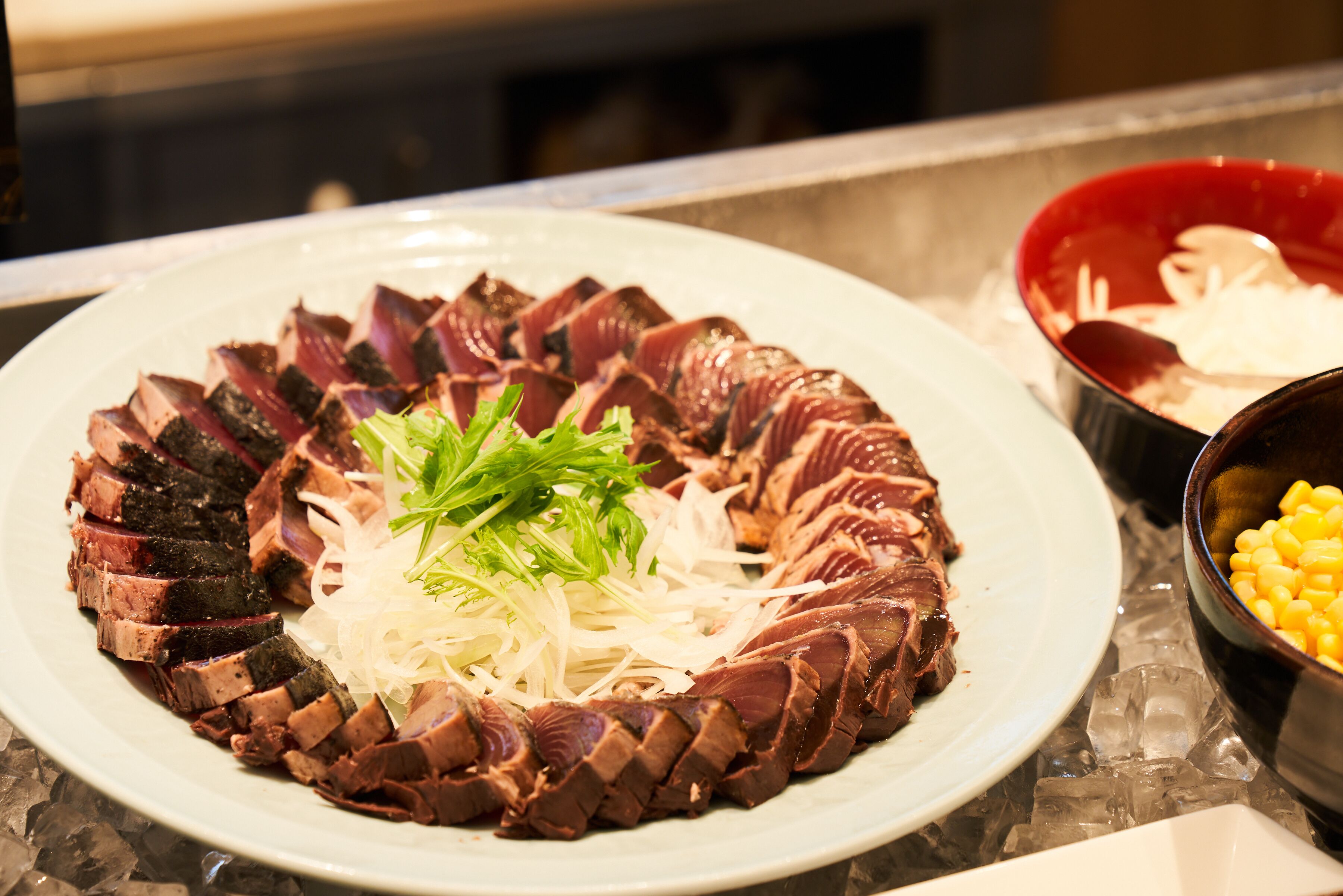 A plate of sliced meat with shredded vegetables and a garnish.