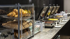 Een buffet met diverse gerechten, waaronder gebak en warme maaltijden, gepresenteerd in transparante containers.
