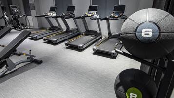 A gym with treadmills, weight machines, and a weight rack.