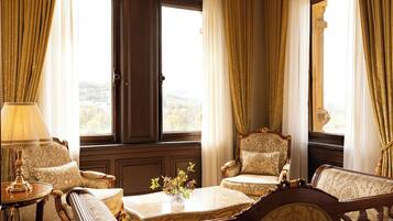 A room with a large window, two armchairs, a small table with a vase, and a lamp.