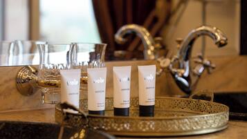 A bathroom vanity with three tubes of body lotion, a glass of water, and a decorative tray.